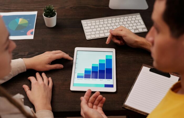 Team members discussing digital graphs on a tablet in a modern office setting.