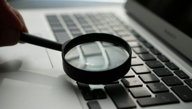 magnifying glass near gray laptop computer