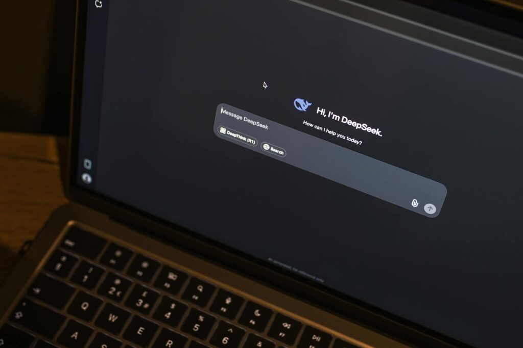 A laptop on a wooden table shows an AI chat interface, featuring the DeepSeek chatbot in action.