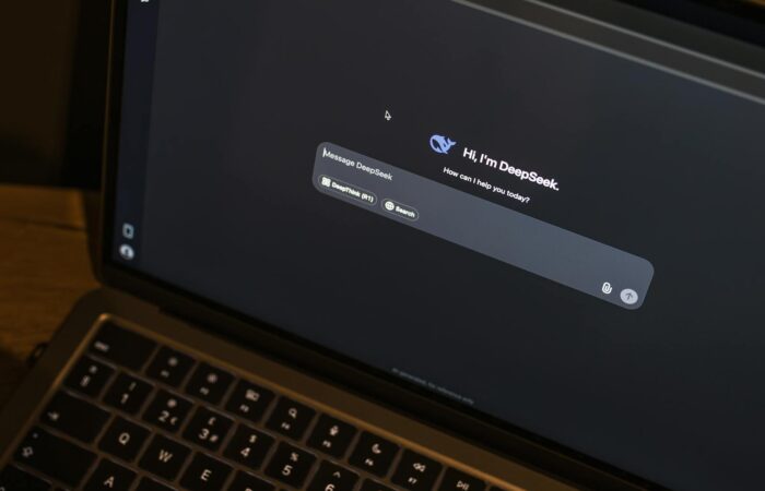 A laptop on a wooden table shows an AI chat interface, featuring the DeepSeek chatbot in action.