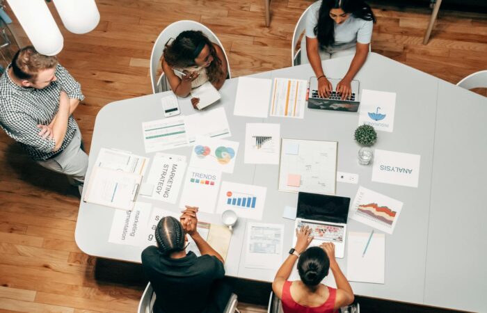 A diverse group working on marketing strategies with charts and laptops in an office setting.