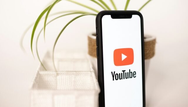 a phone with a youtube logo on it next to a potted plant