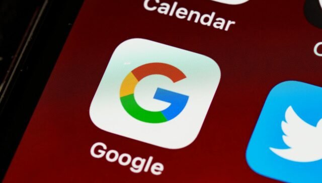Macro view of a smartphone displaying Google and other app icons on the home screen.
