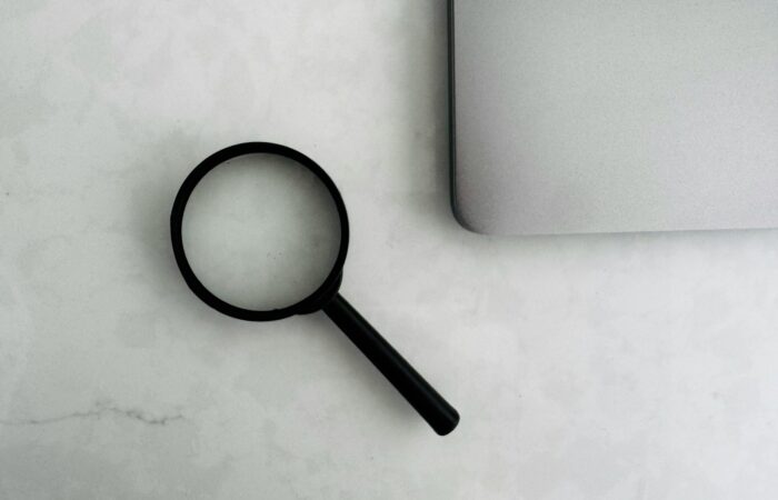 Magnifying glass sits near a laptop on a table.