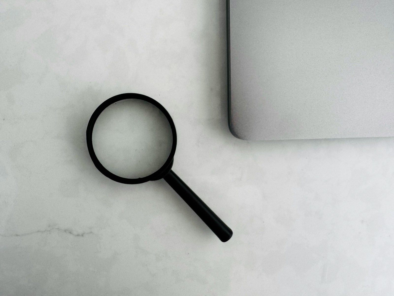 Magnifying glass sits near a laptop on a table.