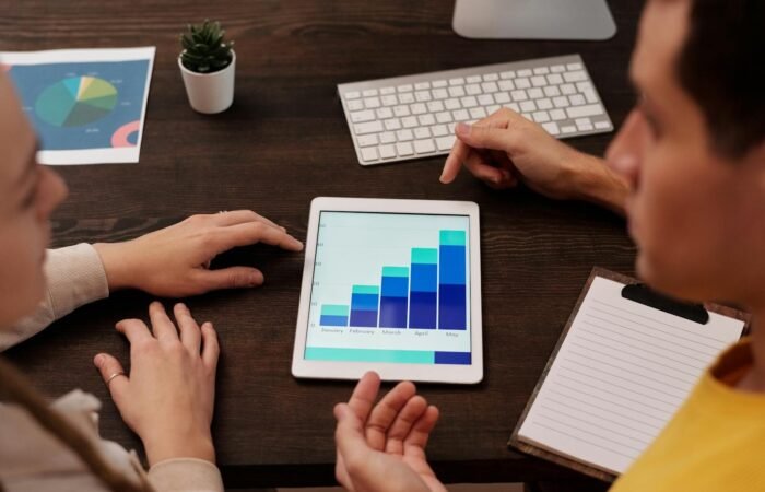 Team members discussing digital graphs on a tablet in a modern office setting.