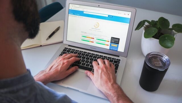 person using macbook pro on white table