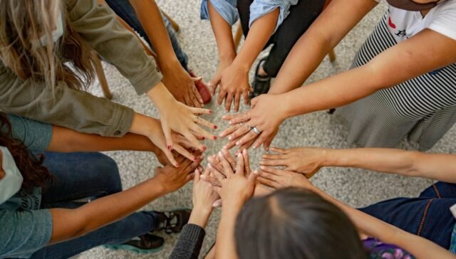 A group of people standing in a circle with their hands together